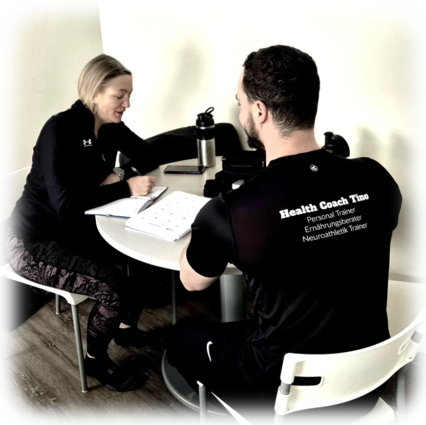 Health Coach Tino und sein Klient führen ein persönliches Gespräch in einer freundlichen und entspannten Umgebung, um gesundheitliche Ziele und den Coaching-Plan zu besprechen.